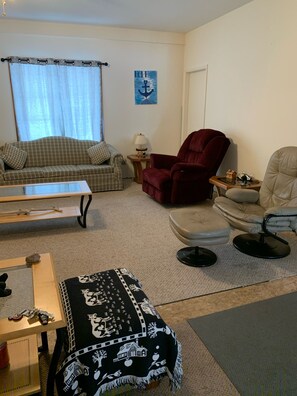 A living room with a sofa, armchairs, a coffee table, and a rug.