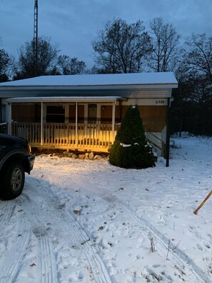 A house with a covered porch, a snow-covered roof, and a mailbox with the number 11389.