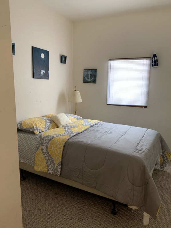 A bedroom with a bed, a nightstand, a lamp, a window with blinds, and wall decorations including a moon and anchor. - Great for big group!! House on 10 acres!! (Irons)