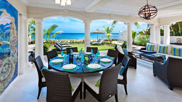 A covered outdoor dining area with a view of the ocean, furnished with wicker chairs and tables, and a ceiling fan overhead. - Stylish Beachfront Villa with Plunge Pool - Still Fathoms (4 bed) (Reeds Bay)