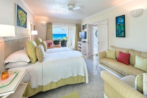 Une chambre d’hôtel avec un grand lit, un canapé, une télévision et un balcon donnant sur l’océan.