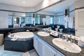 A modern bathroom with a large bathtub, two sinks, and a large mirror.
