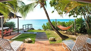 A patio with outdoor seating, a hammock, and a view of the ocean.