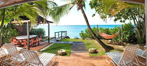 A patio with outdoor seating, a hammock, and a view of the ocean.