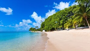 A beach with clear turquoise water, a sandy shore, and lush green trees. - 17th Century Sugar Mill Near Beach - Mullins Mill (Mullins)
