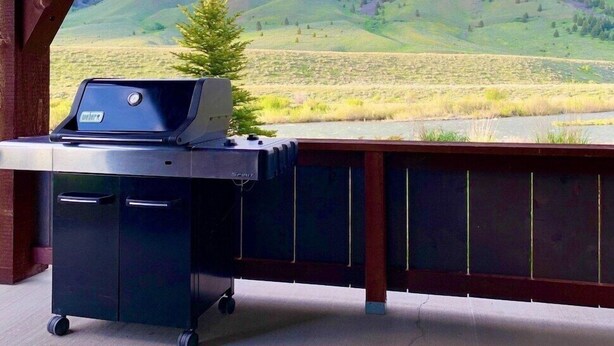 Un barbecue sur un balcon offrant une vue sur un paysage montagneux.
