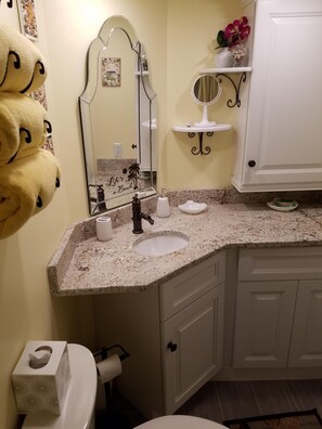 A bathroom with a granite countertop sink, a mirror, a toilet, and a towel rack with towels. - Dave's Vacation Rentals - Palms resort (Myrtle Beach)