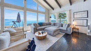 A spacious living room with a large sectional sofa, a round coffee table, and a view of the ocean.