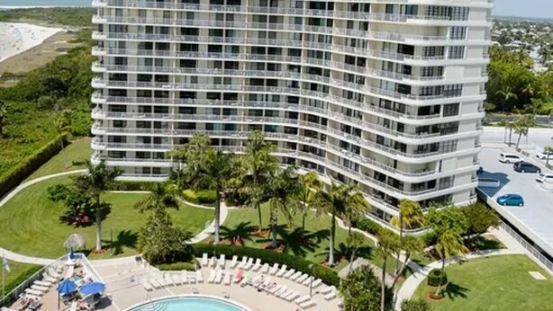A multi-story hotel with a pool area, surrounded by palm trees and a clear sky. - Beautiful Marco Island Renovated Condo, 2 Br 2 Ba, 1704 T4,  Beach & Ocean Views (Marco Island)