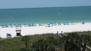 A beach with white sand, blue umbrellas, and a few boats in the water. - Beautiful Marco Island Renovated Condo, 2 Br 2 Ba, 1704 T4,  Beach & Ocean Views (Marco Island)