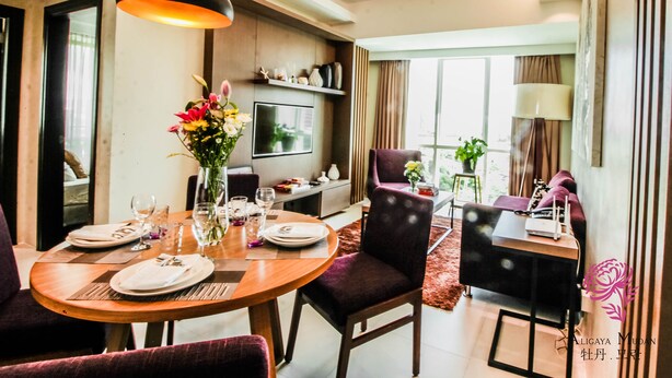 A modern dining area with a round table set for four, a television mounted on the wall, and a large window providing natural light. - A SPACIOUS AND LUXURIOUS APARTMENT W/ 3 BEDROOM (Cebu City)