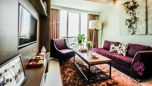 A modern living room with a large flat-screen TV, a sofa, a coffee table, and a large abstract painting on the wall. - A SPACIOUS AND LUXURIOUS APARTMENT W/ 3 BEDROOM (Cebu City)