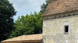 A stone building with a tiled roof, a covered outdoor seating area, and a gravel ground.