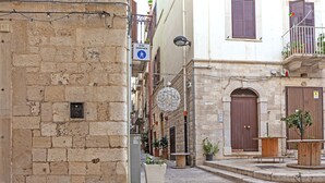 A narrow street with stone buildings, a pedestrian sign, and outdoor seating areas. - B&b Oltre l'Arco (Molfetta)