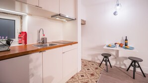 A modern kitchen with a wooden countertop, stainless steel sink, and a small dining area with stools. - Rose 7 Studio Apartment (Lisboa)