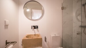 A bathroom with a round mirror, a beige sink, a toilet, and a glass shower enclosure. - Rose 7 Studio Apartment (Lisboa)