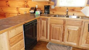 A compact kitchen with wooden cabinets, a dishwasher, a coffee maker, and a sink.