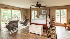A spacious bedroom with a large bed, a ceiling fan, wicker chairs, and a view of the outdoors. - Woods Bay Lookout, Georgian Bay (The Archipelago)