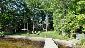 A wooden dock extending into a clear body of water, surrounded by lush greenery and trees. - Woods Bay Lookout, Georgian Bay (The Archipelago)