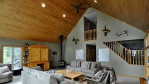 A spacious living room with a high ceiling, a fireplace, a staircase, and a balcony. - Woods Bay Lookout, Georgian Bay (The Archipelago)