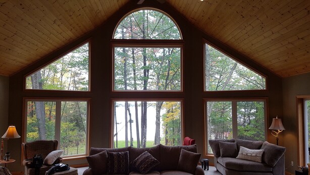 A spacious room with a high ceiling and large windows offering views of a forested area. - Woods Bay Lookout, Georgian Bay (The Archipelago)