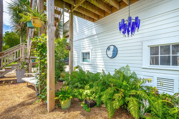 A white house with a porch, wooden staircase, and a blue glass chandelier.