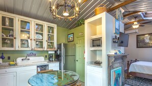 Una cocina compacta equipada con refrigerador, microondas y una mesa de comedor con sillas.