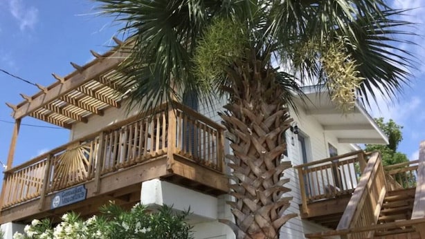 Un edificio de dos pisos con un balcón y una palmera.