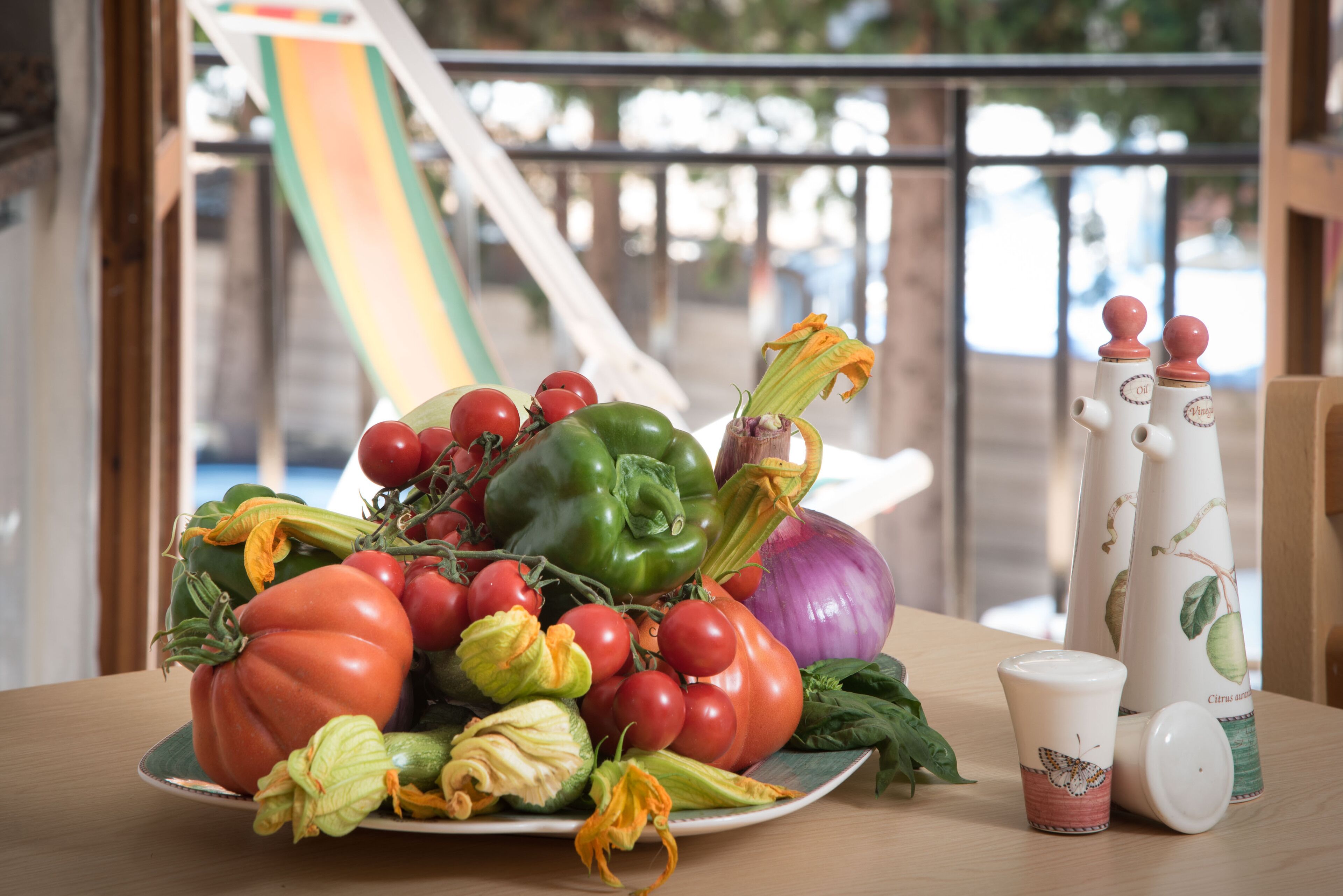 Une assiette de légumes frais et deux salières sur une table.