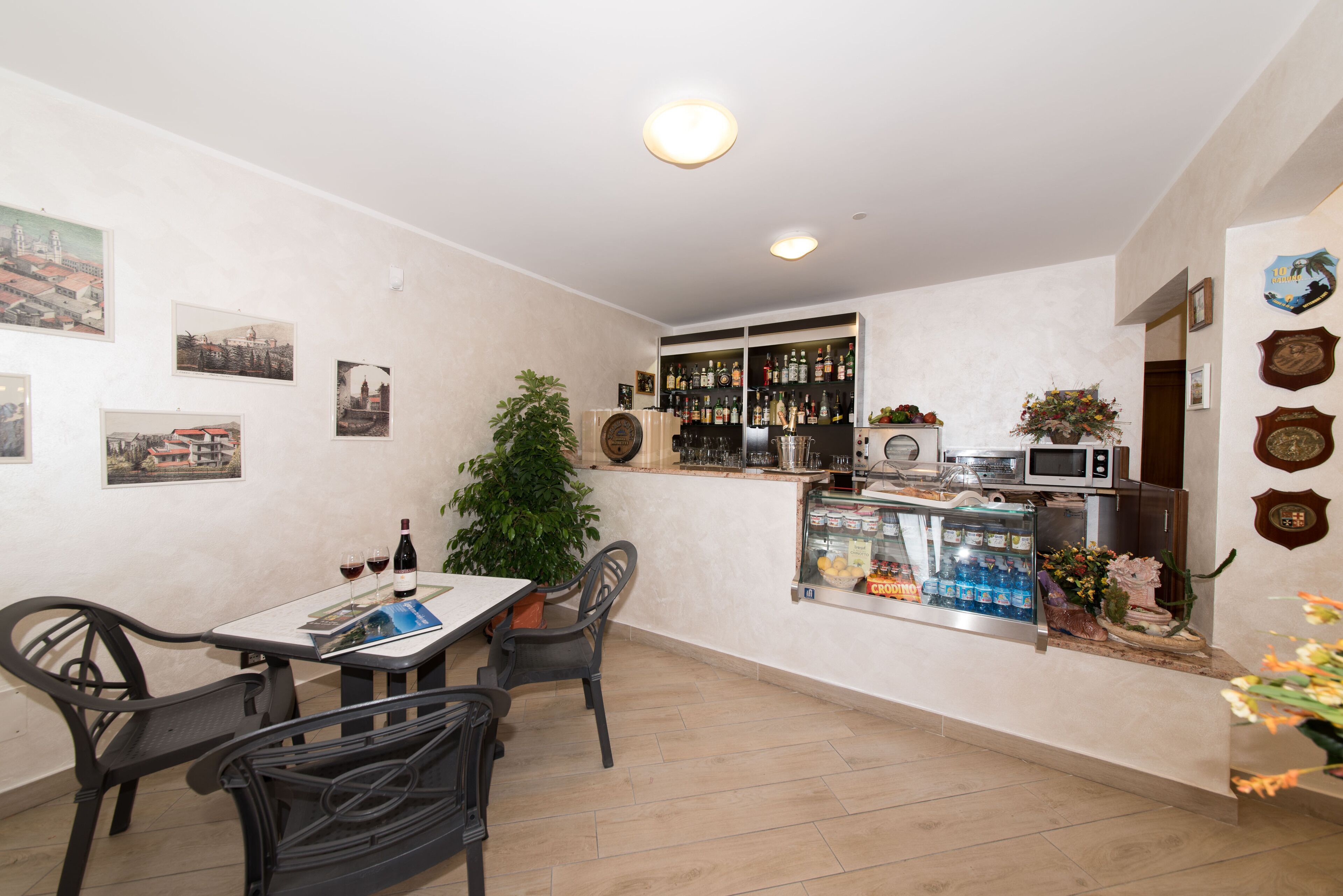 A compact kitchen with a dining area, featuring a refrigerator, microwave, and a small bar area with a display case.