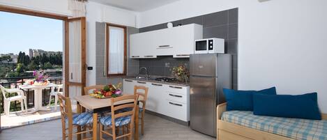 A modern kitchen with a dining area and a sofa.
