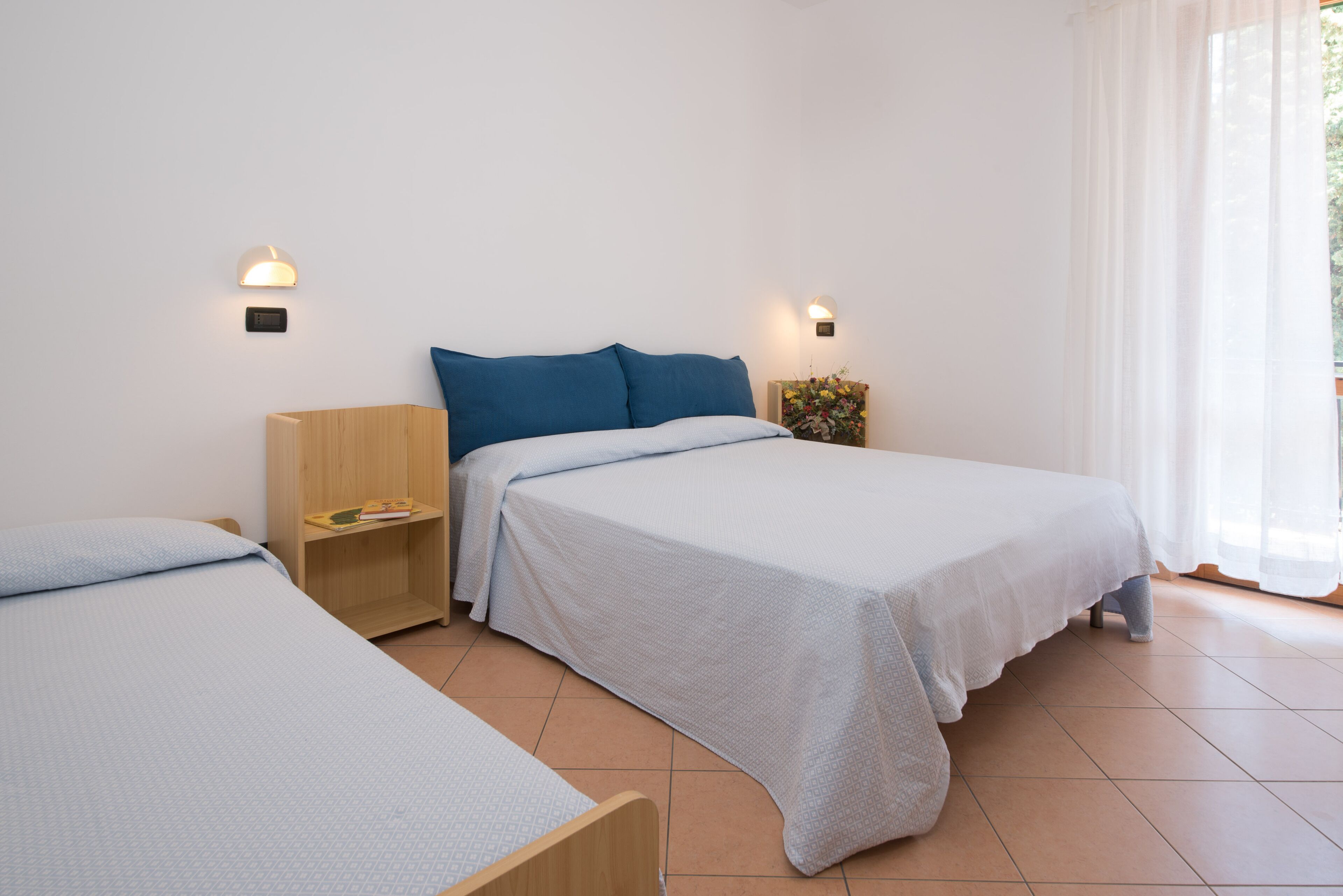 Ein Schlafzimmer mit zwei Betten, einem Holznachttisch, einem kleinen Tisch und einer Wandlampe.