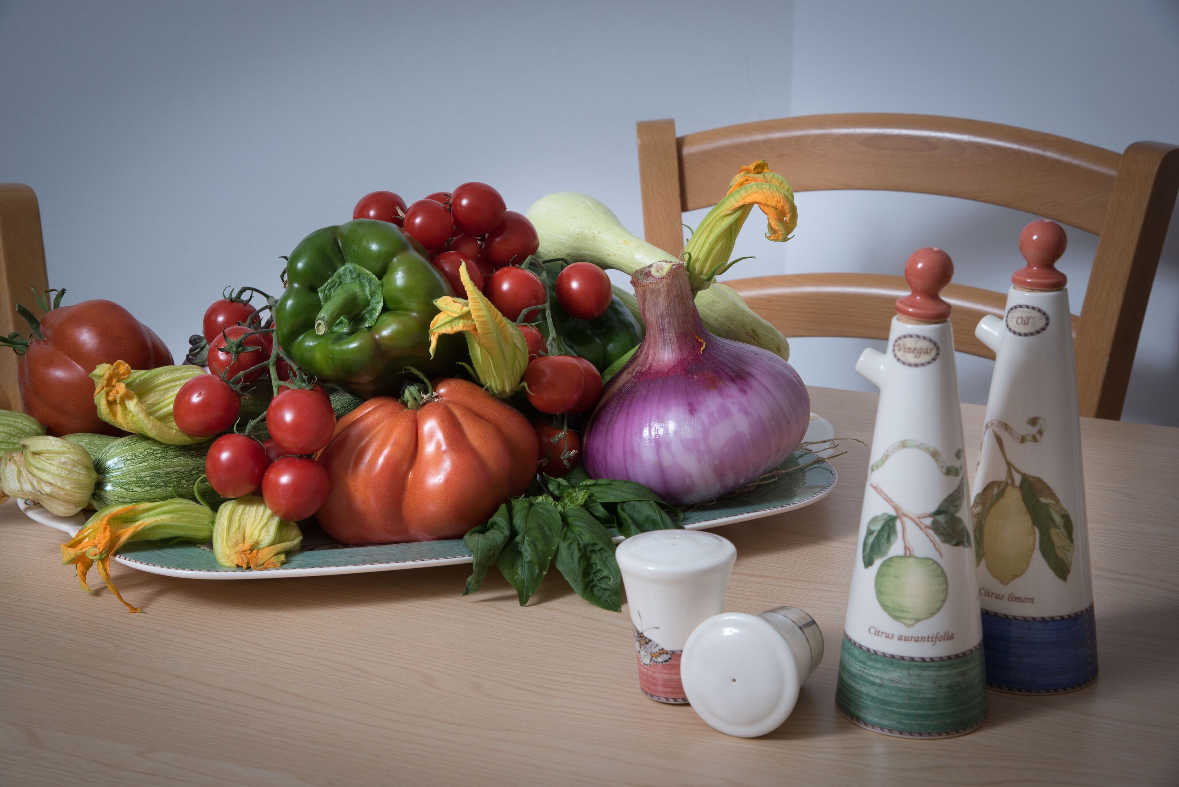 Een tafel met diverse groenten en twee zoutstrooiers.