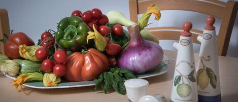 A table with a variety of vegetables and two salt shakers.