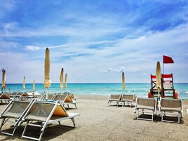 Na praia, espreguiçadeiras, guarda-sóis, bar na praia