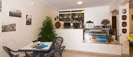 A dining area with a table, chairs, and a bar counter with various bottles and glasses.