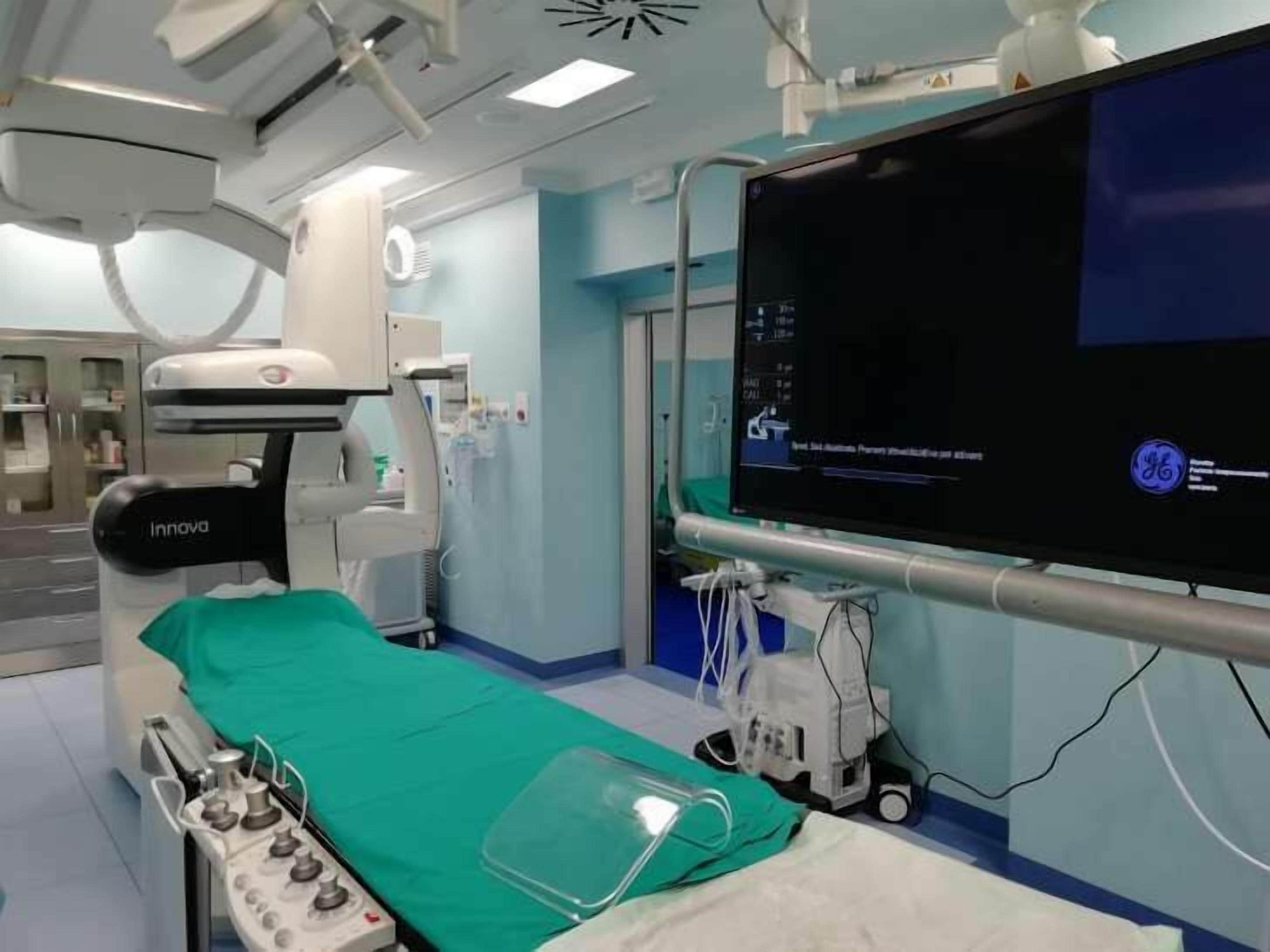 Una sala de diagnóstico por imagen con un escáner de tomografía computarizada, un monitor y una cama para pacientes.