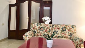 A room with a floral sofa, a potted plant, and a door with a mirror.