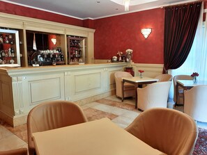 Une chambre d’hôtel comprenant un coin bar, une table à manger avec des chaises et une grande fenêtre avec des rideaux.