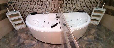A bathroom with two large oval-shaped tubs, a patterned tile backsplash, and a marble floor.
