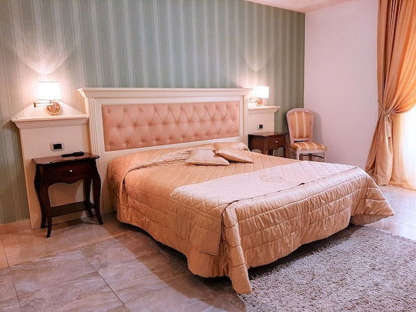 Une chambre bien rangée, avec un grand lit, deux tables de chevet, une chaise et une petite table d’appoint.