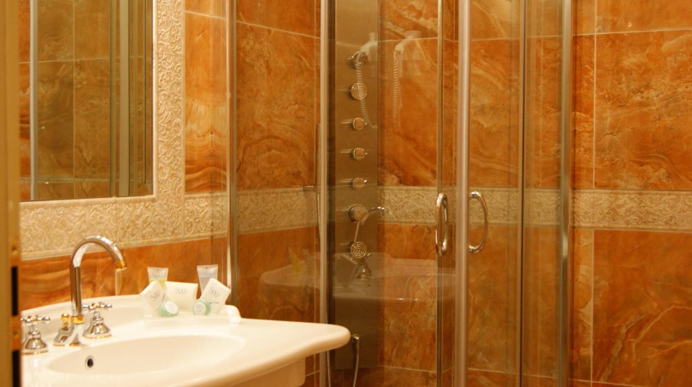 A bathroom with a sink, mirror, and shower enclosure.