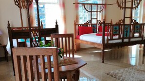 A spacious room with a large bed, a dining table with chairs, and a ceiling fan. - Salhiya Lodge - Hostel (Bububu)