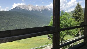 A mountain view from a wooden cabin with a wooden railing.