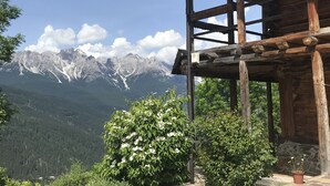 A wooden cabin with a stone patio and a mountain view.