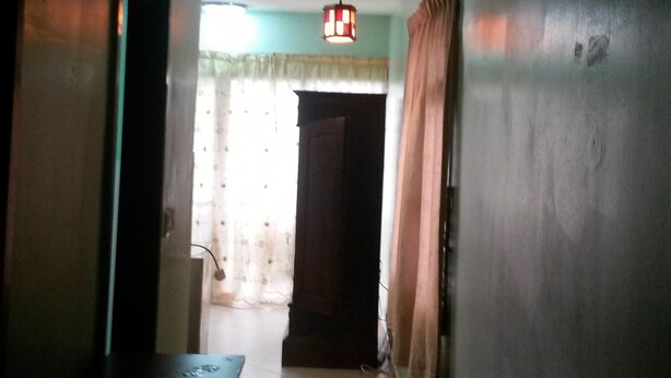 Un pasillo con una lámpara en el techo, una puerta y una pared con cortinas.