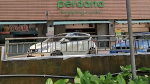 Un centro comercial con un letrero que dice 'psc perdana' y una camioneta blanca estacionada al frente.