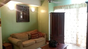 Una sala de estar con un sofá color beige, un aparador de madera oscura y una bolsa negra sobre una mesa de madera.