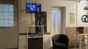 Une chambre comprenant un lit, un téléviseur fixé au mur, un bureau avec une chaise et une fenêtre avec des stores.