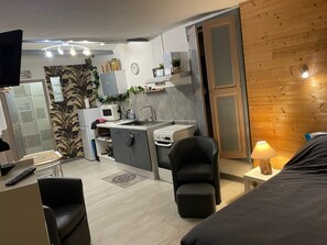 A compact hotel room with a kitchenette, a dining area, and a bed.